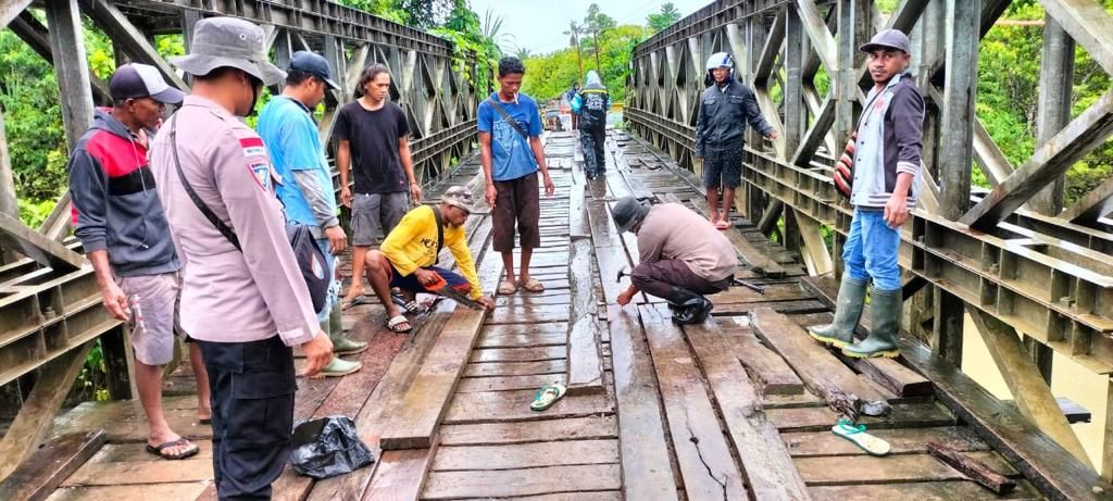 Suasana warga bersama anggota Polsek Arso Timur memperbaiki jembatan Kali Bawen yang rusak tersapu arus luapan air sungai 