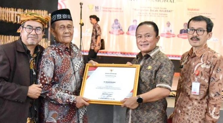 Sekda Kuningan, H. Dian Rachmat Yanuar menyerahkan penghargaan kepada seorang tokoh di sela-sela peringatan Bahasa Indung Internasional.