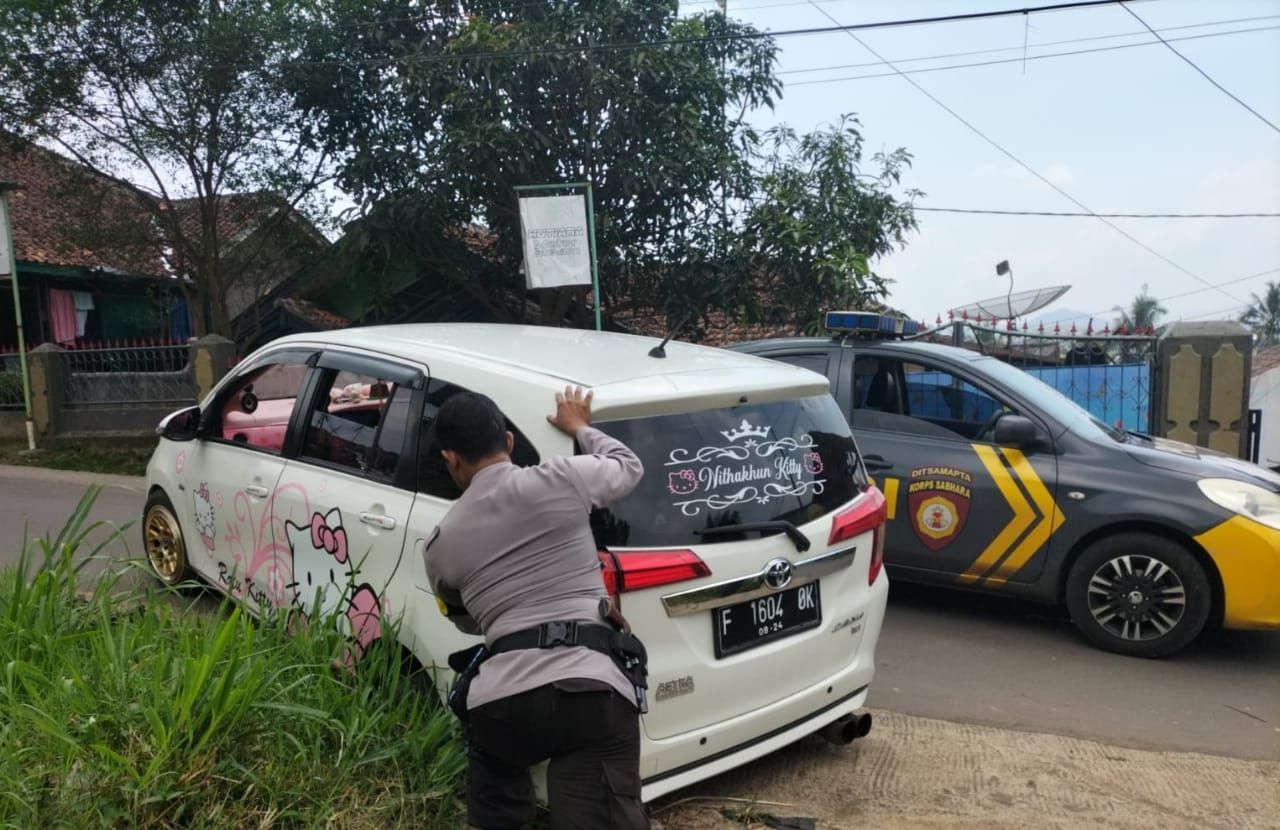 Petugas Patroli Polres Sukabumi Kota tengah mendorong mobil yang masuk selokan di Kecamatan Citamiang Kota Sukabumi