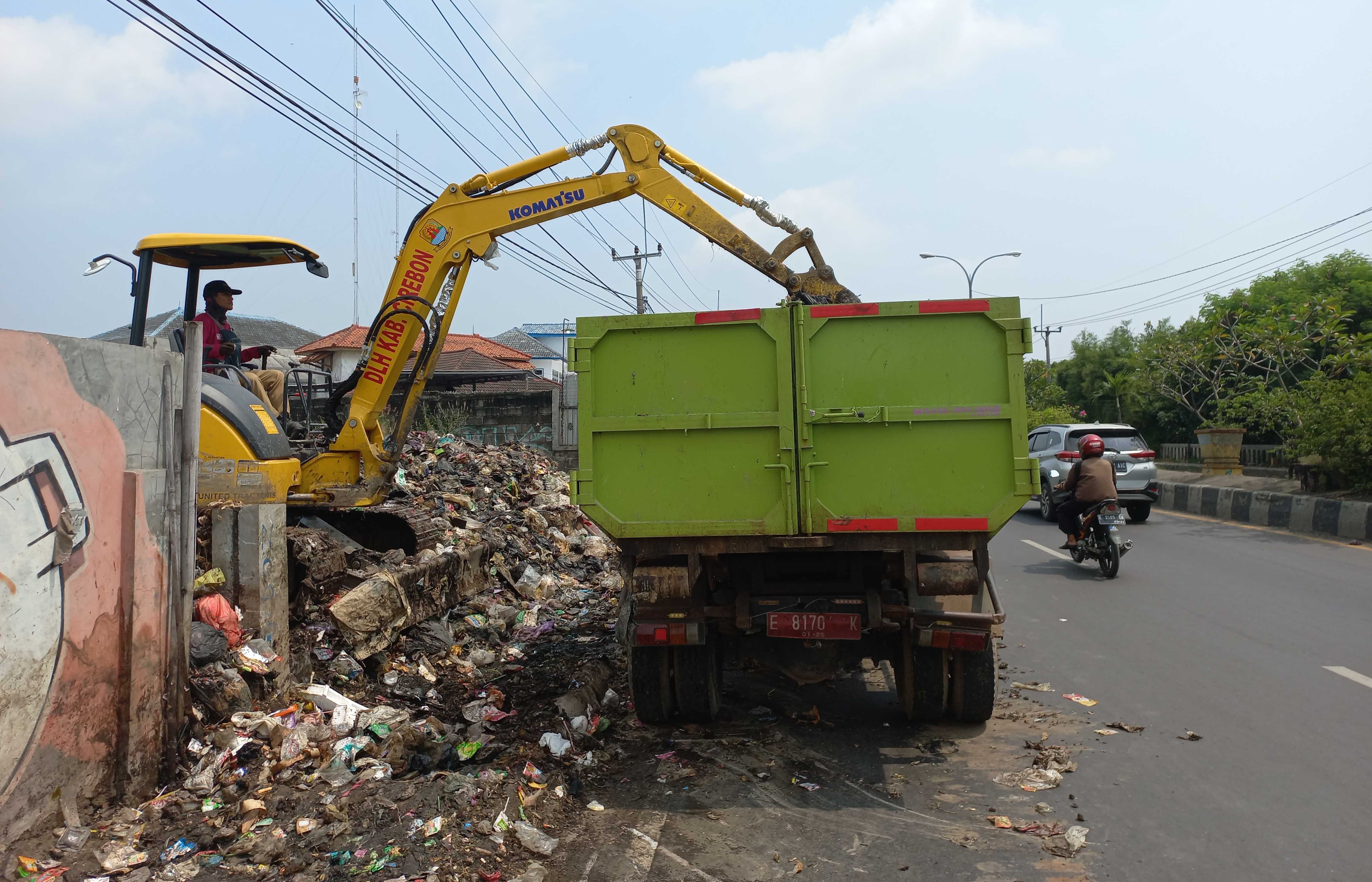 PETUGAS dari DLH Kabupaten Cirebon membersihkan sampah liar di sepanjang ruas jalan nasional atau By Pass Kedawung, Senin (20/3/2023).*