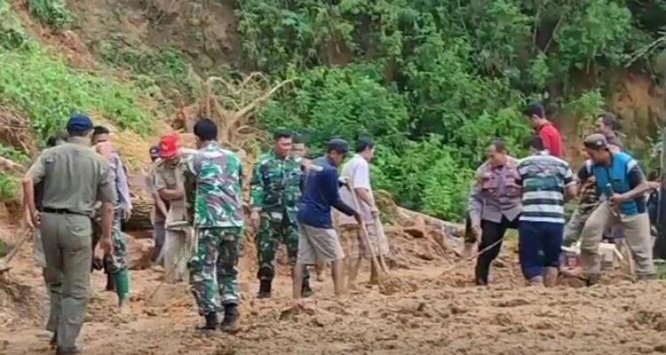 Petugas gabungan masih terus berupaya memotong batang kayu Pohon Karet yang ikut roboh terbawa tanah longsor yang menutup salah satu akses ke lokawisata. 