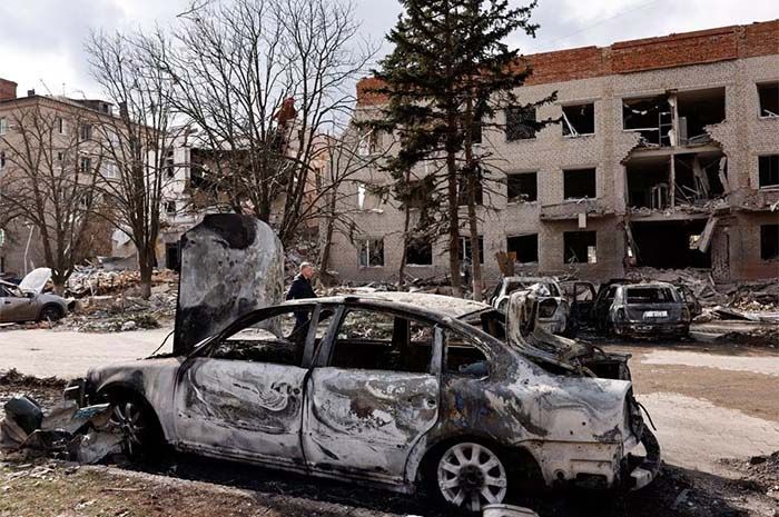 Seseorang berjalan di samping mobil yang rusak setelah penembakan mematikan di sebuah gedung kantor militer, di tengah serangan Rusia, di Sloviansk, Ukraina, 27 Maret 2023.