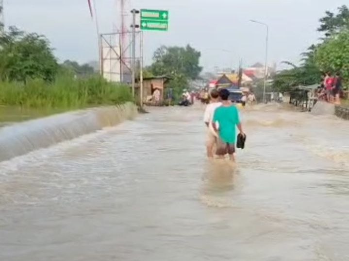 Limpasan Sungai Tuntang yang naik ke jalan raya menyebabkan pengendara mesti berhati-hati saat melintas.