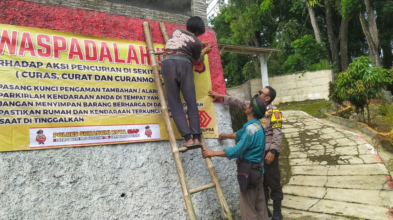 Polisi Polsek Sukabumi tengah memasang spanduk himbauan waspada tindakan kejahatan