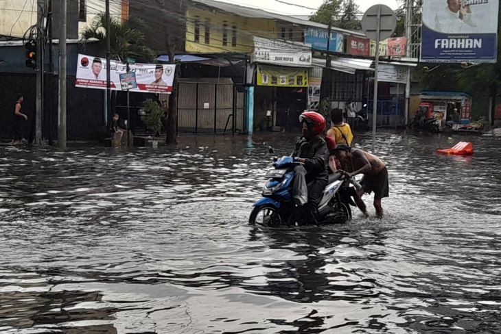 Seorang ibu pengendara sepeda motor yang memaksa menerobos ruas Jalan Kopo yang tergenang air mengalami mogok dan terpaksa didorong.