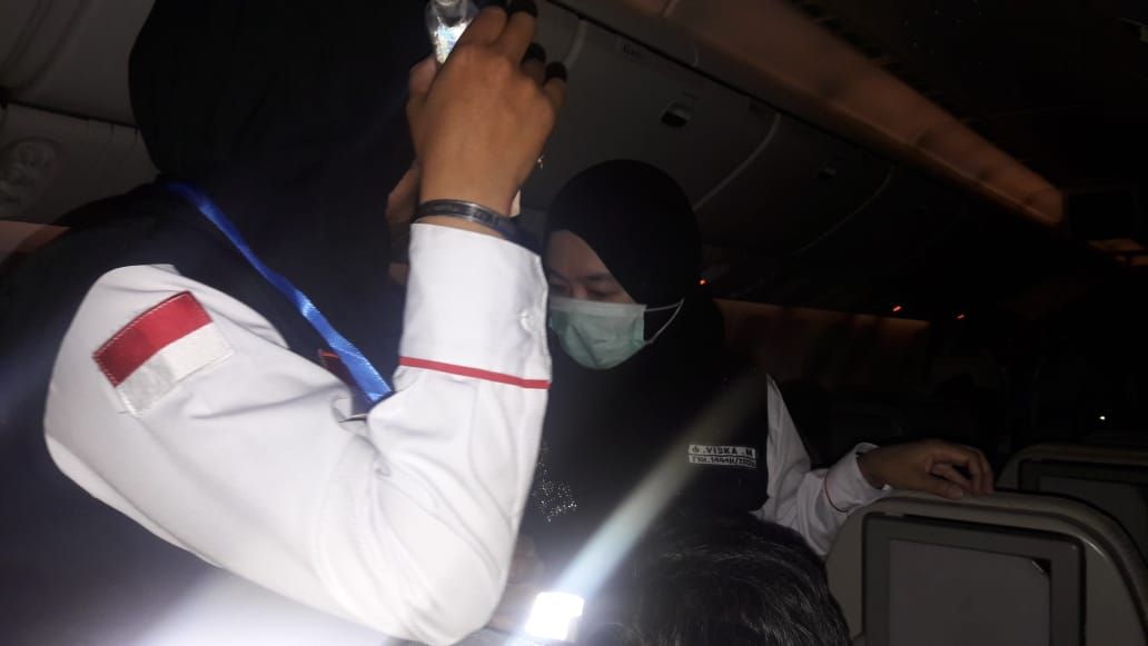 Dr Viska (bermasker) nampak sedang menangani penderita penurunan tekanan darah di atas pesawat  Saudi Air yang terbang membawa 480 Jemaah calon haji Kloter 16 Kota Bandung Selasa tengah malam (31/05)./Ofhar