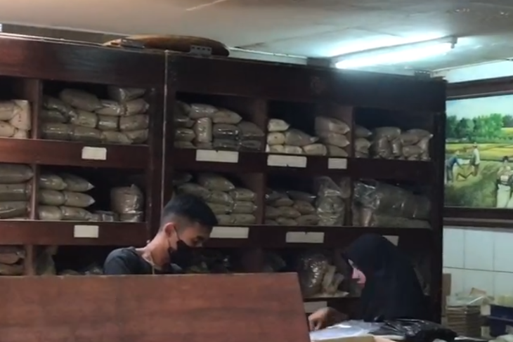 Pekerja Toko Jamu Babah Kuya di Jalan Pasar Barat belakang Pasar Baru Bandung tengah menimbang jamu pesanan pembeli.