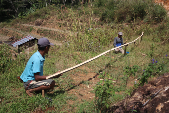 Rikardus dan Albert Rabilang sedang menyambung belahan bambu untuk alirkan air