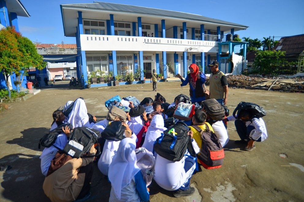 Sejumlah siswa mengevakuasi diri dengan menutup kepala mereka dengan tas saat simulasi gempa dan tsunami di SMPN 4 Padang, Sumatera Barat, Kamis, 13 Juli 2023.