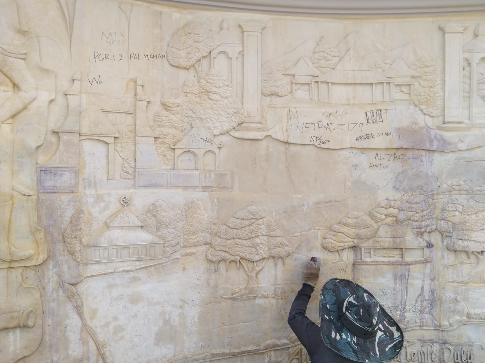 Seorang pekerja tengah membersihkan coretan yang ada di relief sejarah talaga di Alun-Alun Talaga, Senin 24 Juli 2023. Relief tersebut menjadi korban aksi vandalisme orang tidak bertanggung jawab.