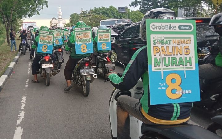 Konvoi para mitra driver online Grab Bike melintasi depan kantor Gubernur Aceh sembari membawa banner yang bertulisan "Grab Bike Hemat, Sobat Hemat Paling Murah, Tarif 8 ribuan," di punggungnya. Kamis, 10 Agustus 2023.