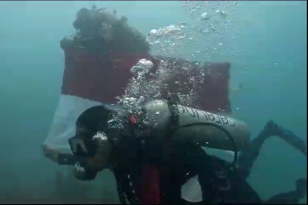 Dua anggota POSSI Banten mengibarkan bendera merah putih di bawah laut