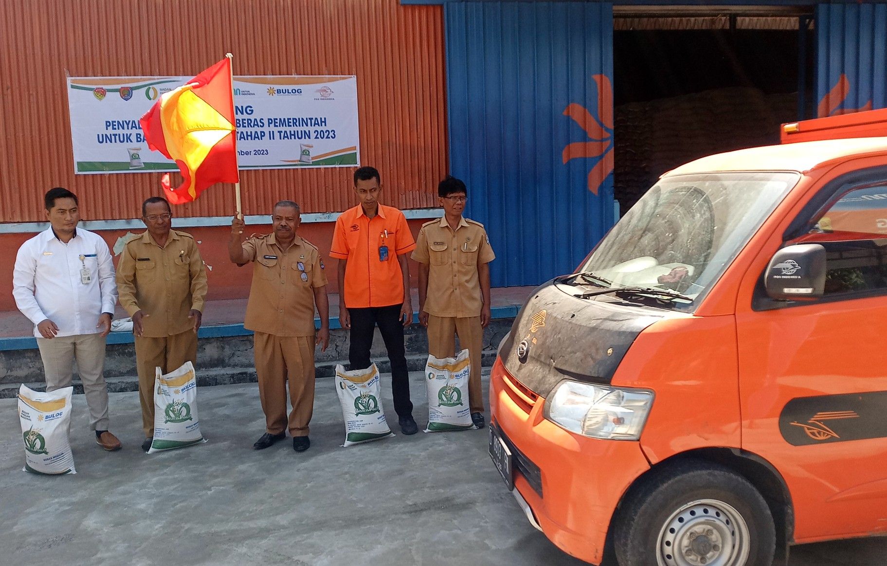 Asisten II Setda Alor, Dominggus Asadama mengangkat bendera melepas angkutan penyaluran bantuan pangan di Kantor Bulog Kalabahi