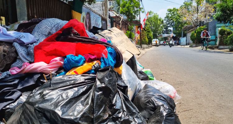 Pesepeda hendak melintasi tumpukan plastik dan kain di pinggir Jalan Bojongloa, Kota Bandung, Selasa, 3 Oktober 2023. Membuang sampah sembarangan-di antaranya melempar dari kendaraan-di Kota Bandung terancam sanksi denda.
