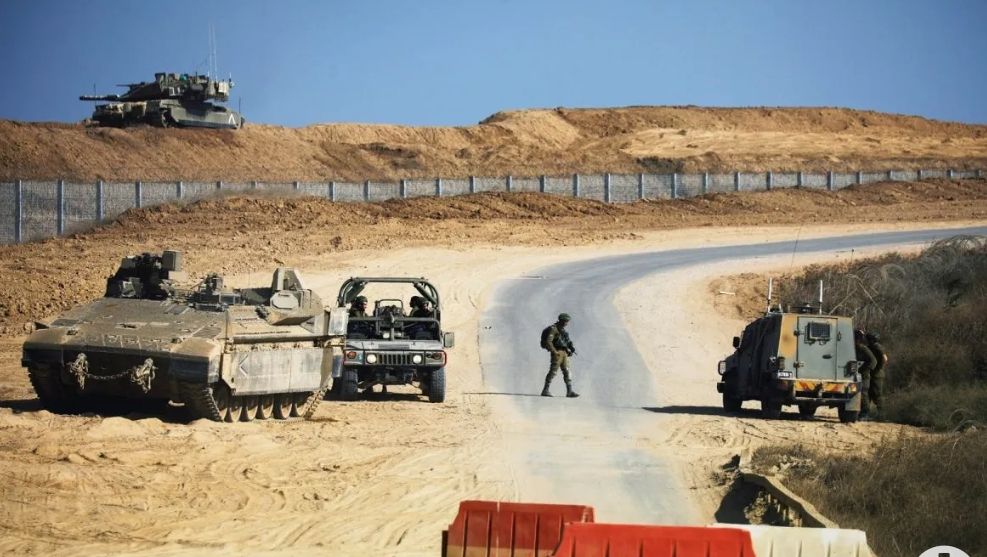 Seorang prajurit Israel berjalan di sebuah jalan saat rekannya duduk di dalam mobil jip militer yang dekat lokasi dimana Israel menemukan terowongan lintas perbatasan baru dari Jalur Gaza 