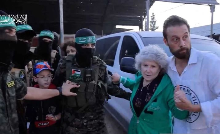 Anggota Hamas menggiring para sandera yang diculik pada 7 Oktober untuk diserahkan ke Palang Merah Internasional di sebuah lokasi yang dirahasiakan di Jalur Gaza, Jumat, 24 November 2023 waktu setempat.​​​​​​​ 