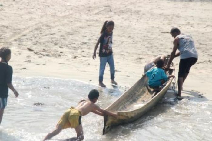 Seorang nelayan di Ritaebang tengah menarik sampannya dibantu anak-anak pantai.//