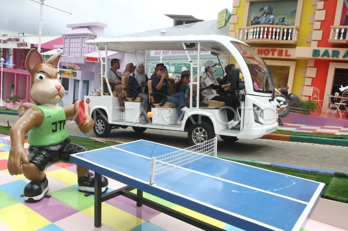 Wisatawan melintasi area wisata dunia fantasi dengan mobil listrik di layanan wahana wisata tanpa turun atau drive thru di Jatim Park 2, Batu, Jawa Timur.