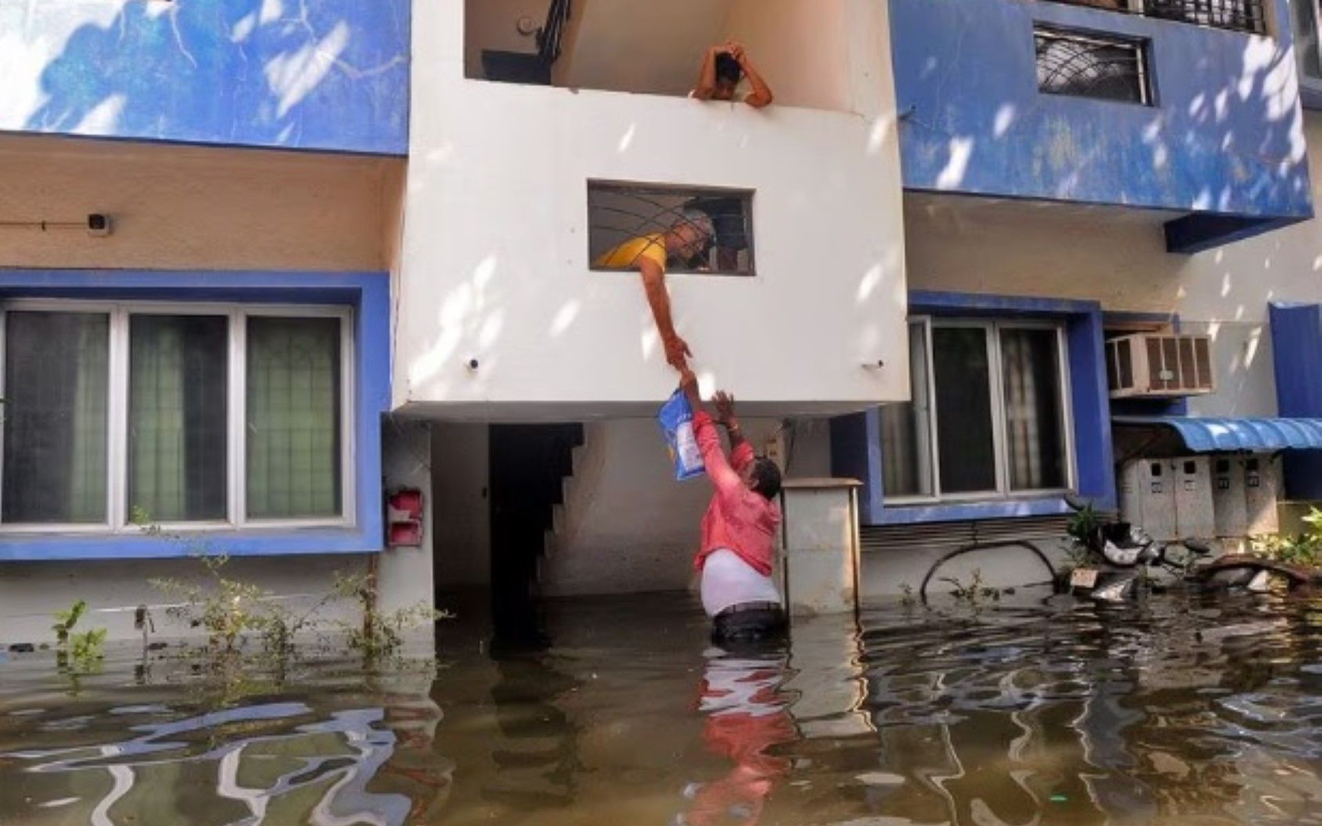 Seorang sukarelawan menawarkan bantuan makanan kepada seorang warga setelah rumahnya sebagian terendam akibat hujan lebat yang disebabkan oleh Topan Michaung, di Chennai, India.
