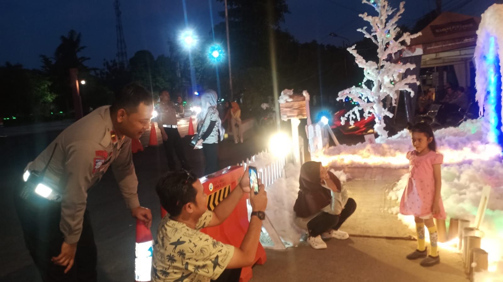 Ipda Sandi melihat langsung antusias orang tua mengambil gambar anaknya di depan Posko Pelayanan Terpadu Simpang Lima Purwodadi bertema Pororo ini.