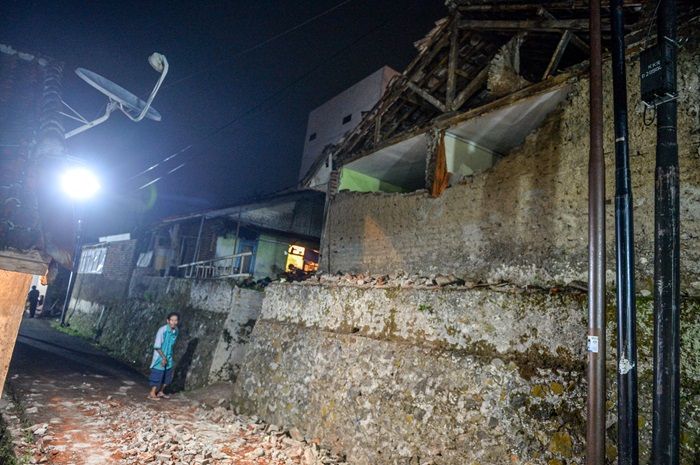 Warga berada di samping rumah yang rusak pascagempa di Babakan Hurip, Kabupaten Sumedang, Jawa Barat, Minggu, 31 Desember 2023.
