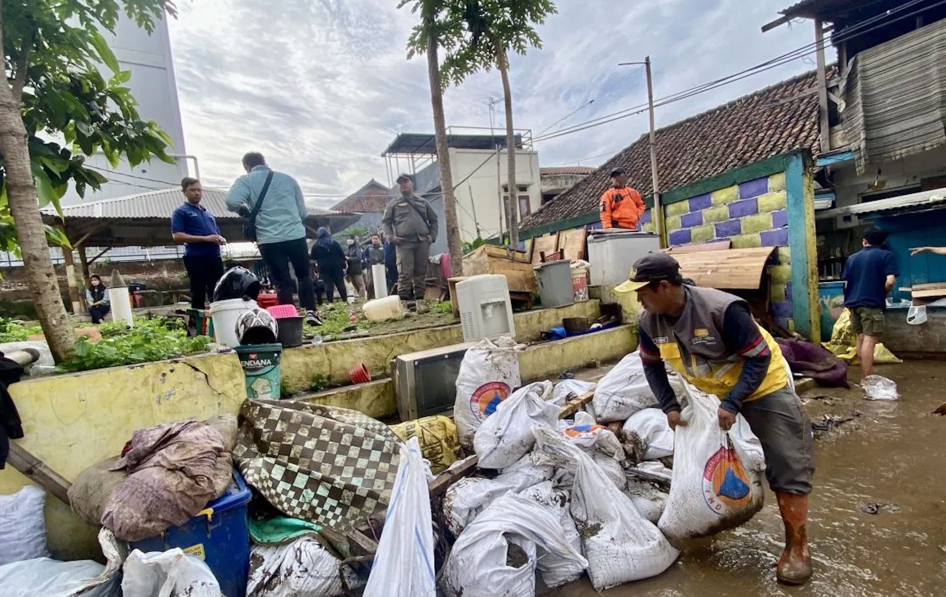 Seorang petugas kebersihan menangani material lumpur di area pemukiman warga setelah banjir di Kelurahan Braga, Kecamatan Sumurbandung, Kota Bandung, Jawa Barat, Jumat (12/1/2024).