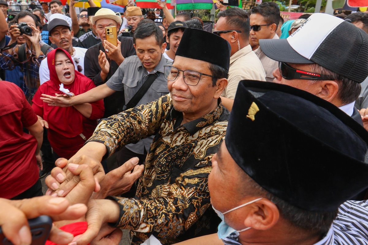 Calon wakil presiden nomor urut 3 Mahfud MD (tengah) menyalami pendukungnya saat berkampanye di hadapan masyarakat nelayan dan petani di Tembokrejo, Muncar, Banyuwangi, Jawa Timur, Jumat, 29 Desember 2023.