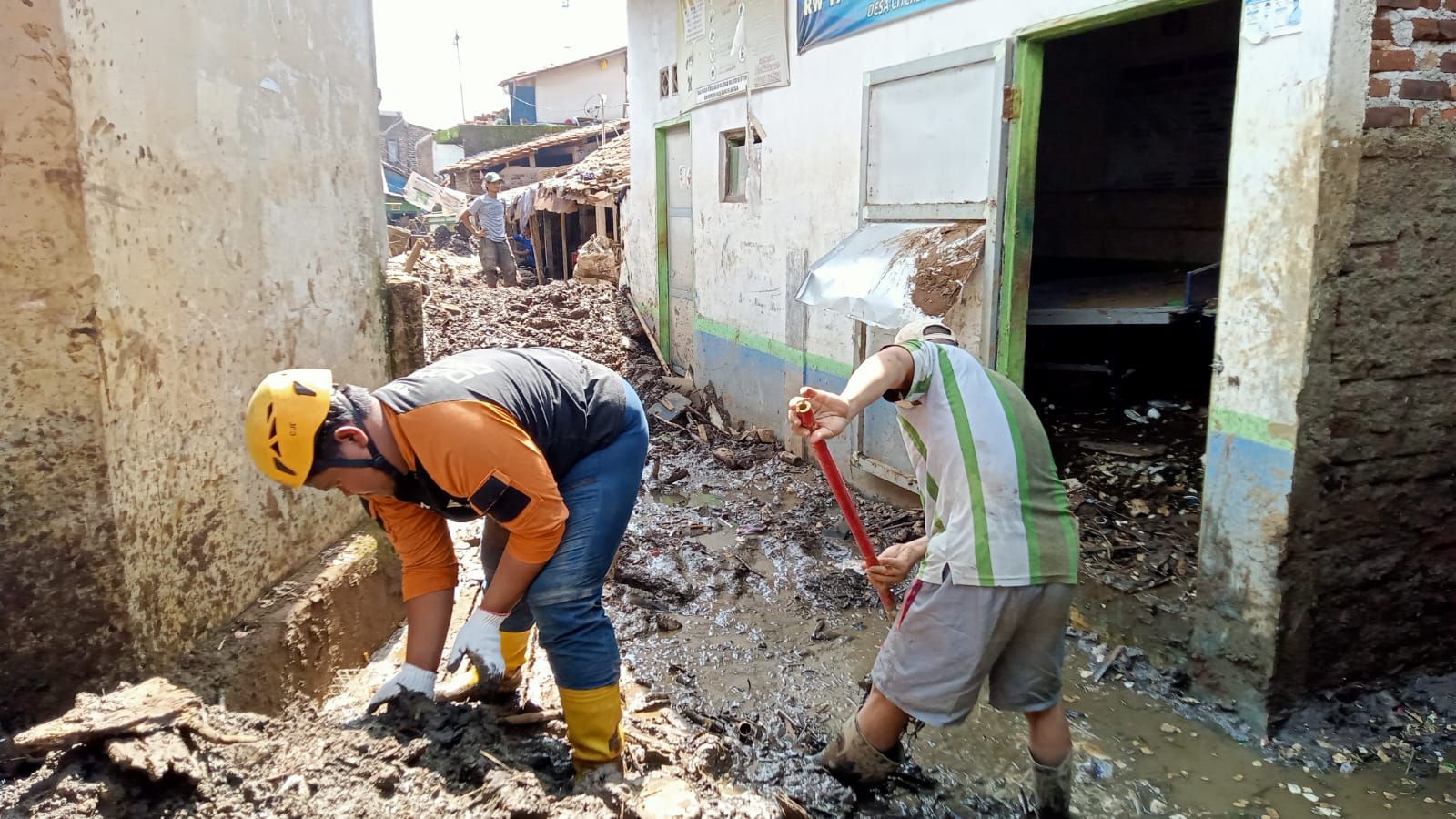Warga dibantu petugas bekerja bakti membersihkan sisa banjir di Desa Citeureup, Kecamatan Dayeuhkolot, Kabupaten Bandung, Selasa, 16 Januari 2024.
