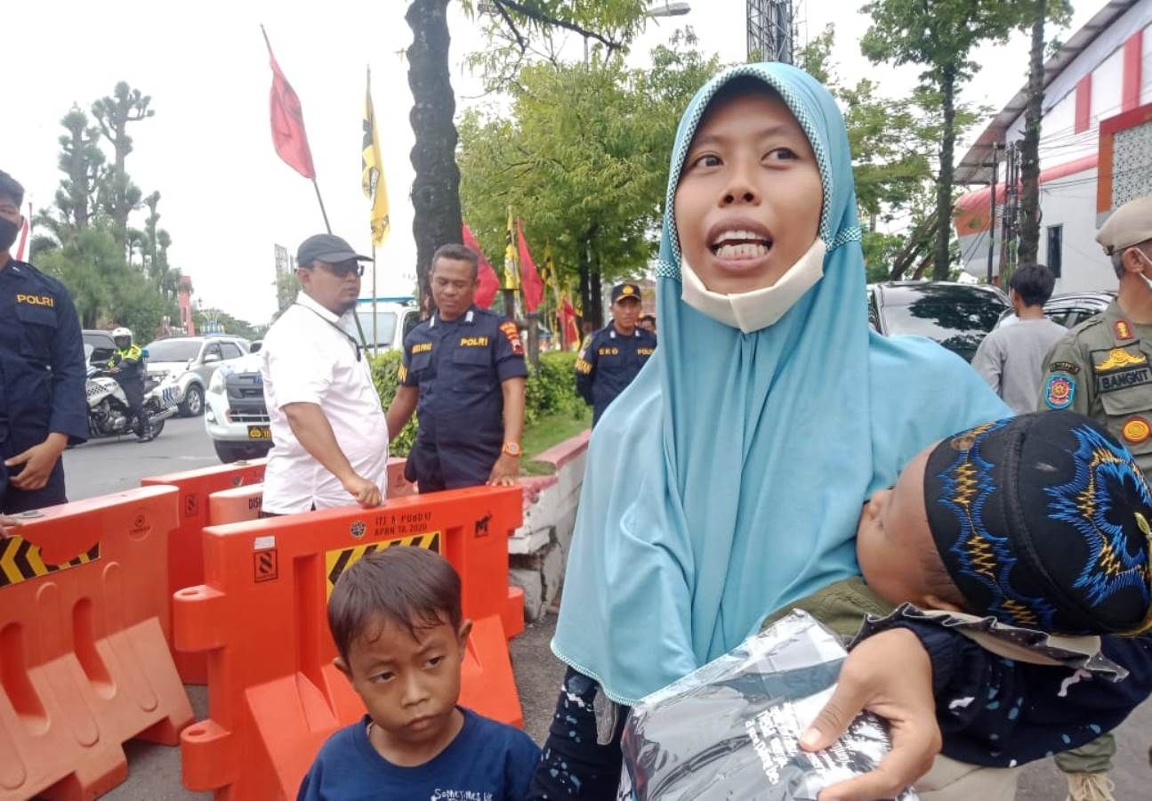 Seorang ibu dengan dua anaknya saat mendapatkan kaos dari Presiden Joko Widodo.