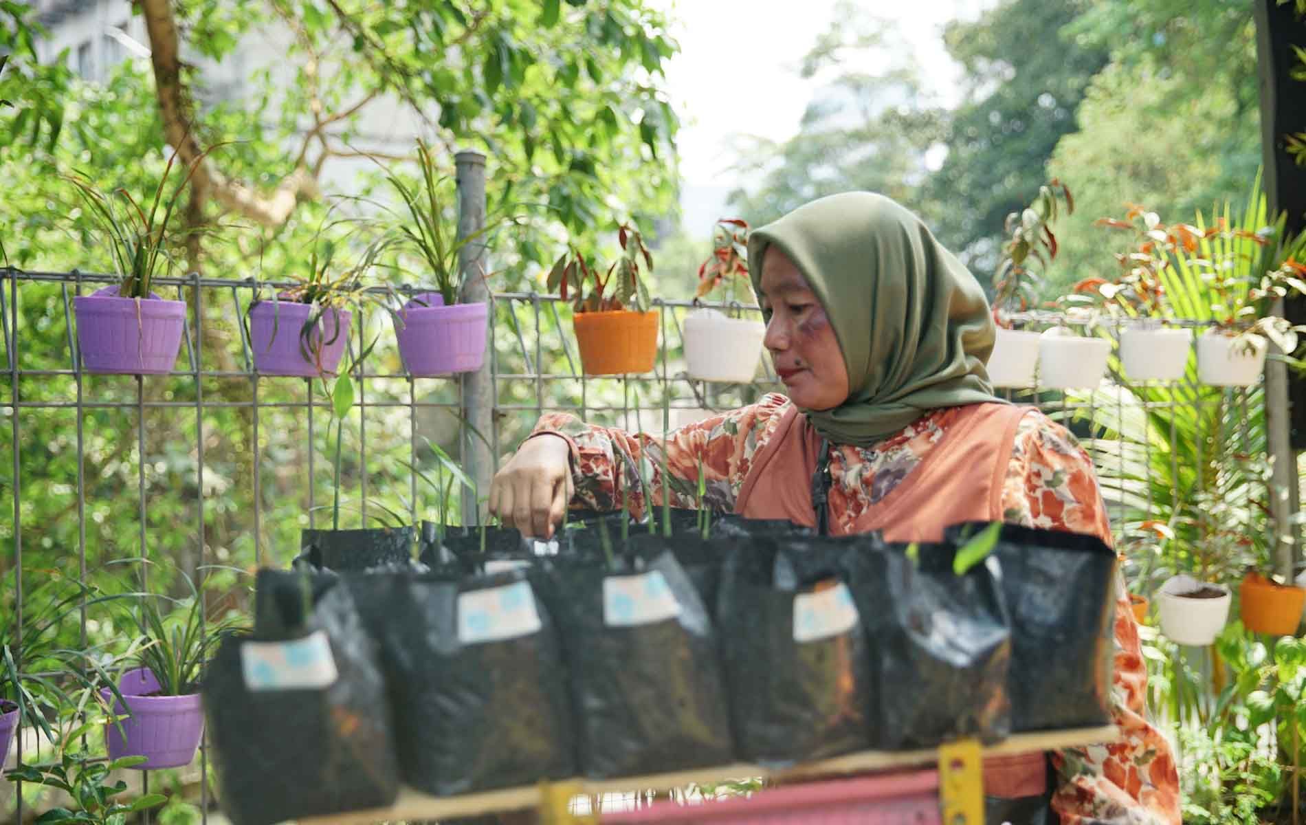 Seorang Ibu sedang merawat tanaman di Kampung Palm Eco Green Village Malang