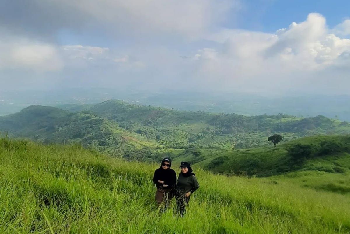 Pesona keindahan Gunung Pangradinan terlihat dua orang pengunjung sedang berswa foto diatas puncak Gunung Pangradinan.