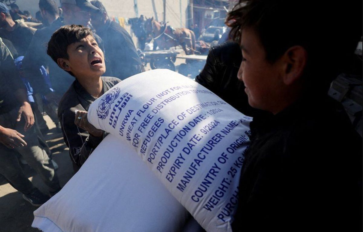 Warga Palestina berkumpul untuk menerima sekantong tepung yang didistribusikan oleh Badan Bantuan dan Pekerjaan PBB (UNRWA), di tengah konflik, di Rafah di selatan Jalur Gaza, Kamis, 1 Februari 2024.