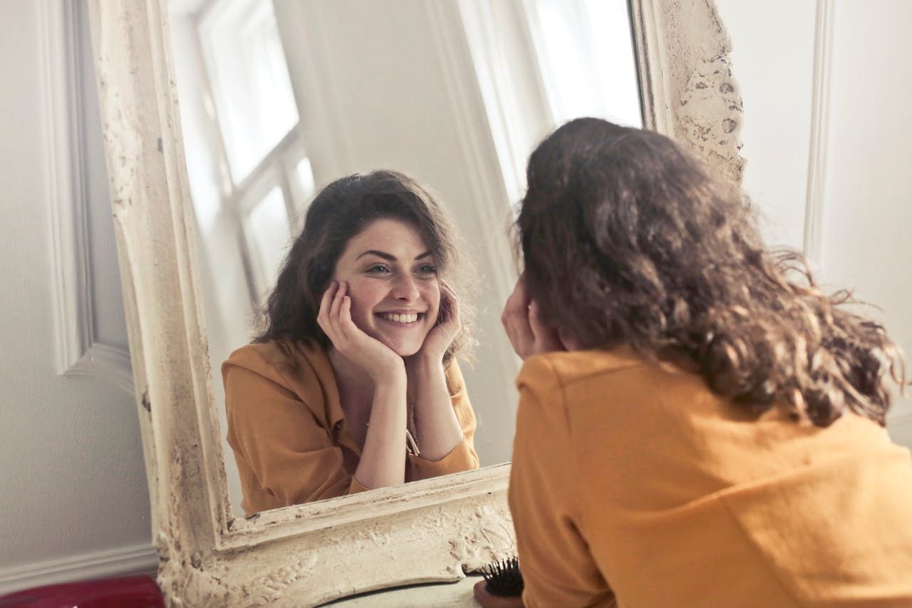 Ilustrasi seorang perempuan berafirmasi positif lewat cermin.