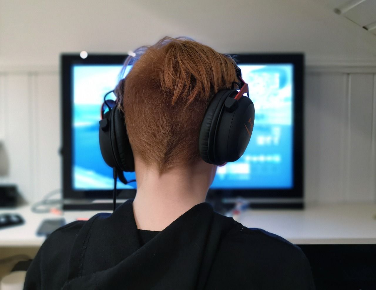 Ilustrasi seorang remaja sedang memakai headpohone saat asik dengan permainan dengan layar televisi.