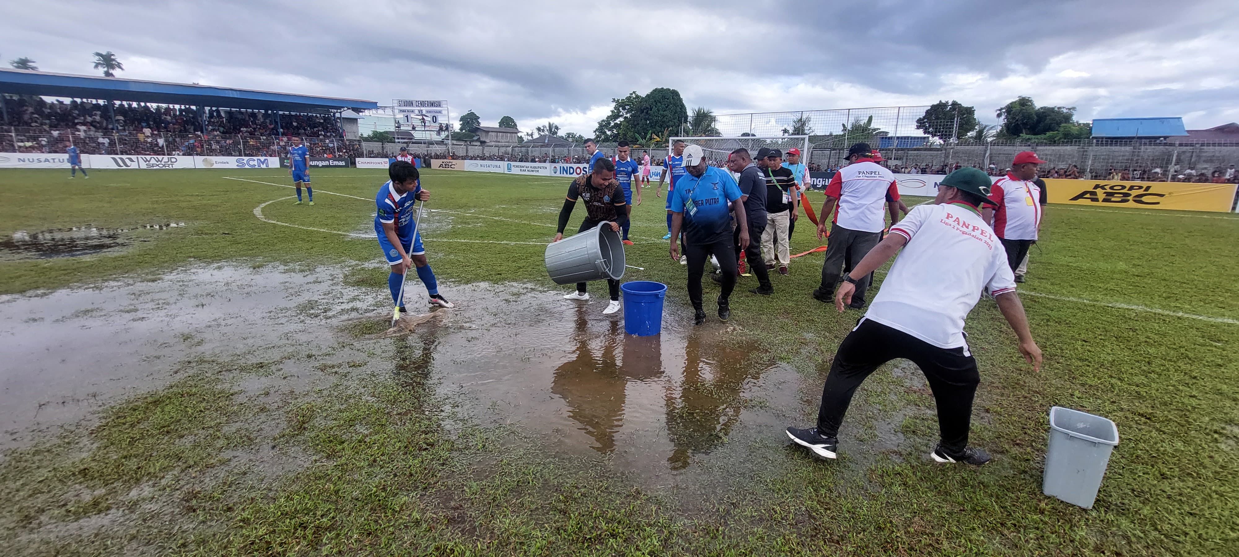 Panpel bersama pemain ketika saling membantu menguras genangan air di  sepanjang badan lapangan akibat hujan deras melanda Stadion Cenderawasih, Biak Numfor, Papua 