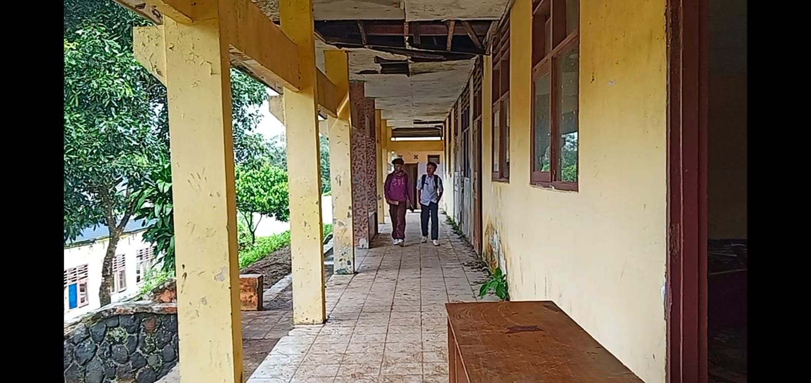 Dua pelajar SMPN Jampang tegah melintasi ruangan sekolah yang rusak