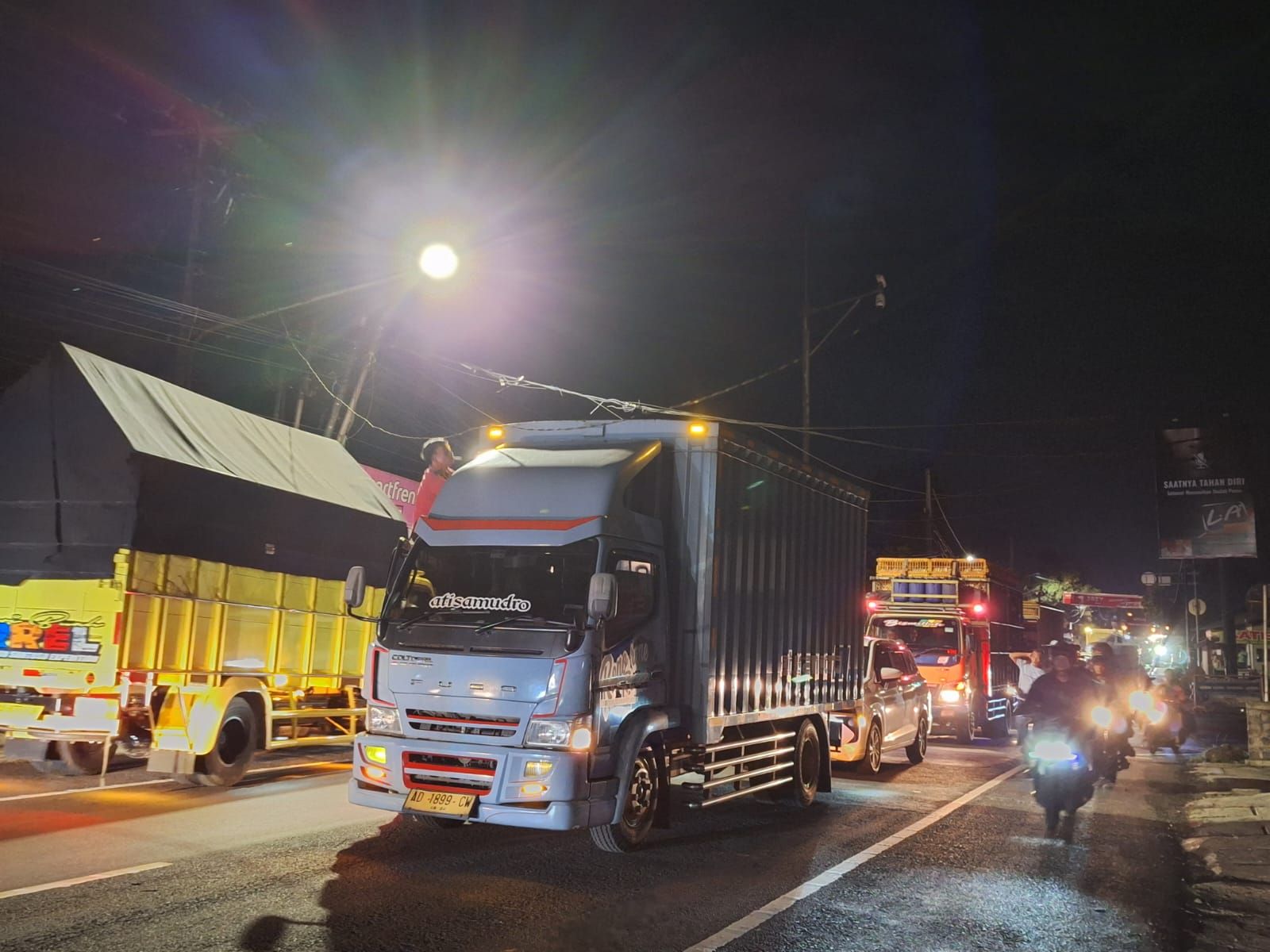 Kondisi jalan raya nasional saat sebuah truk berusaha menghindari kabel yang menjuntai ke jalan akibat tiang listrik di jalan pasar Sindangkasih jatuh melintang ke jalan.
