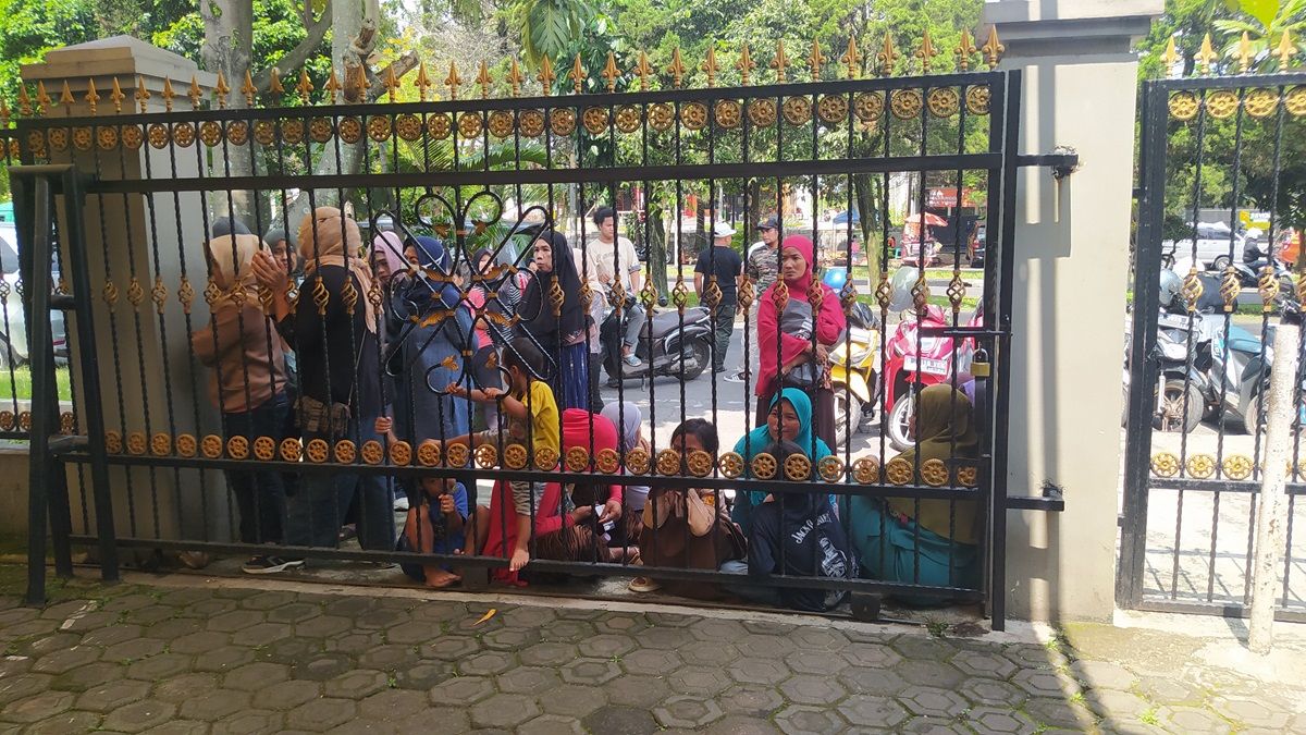 Sejumlah warga masih antre di luar pagar Masjid Mubarak untuk menukarkan kupon sembako.
