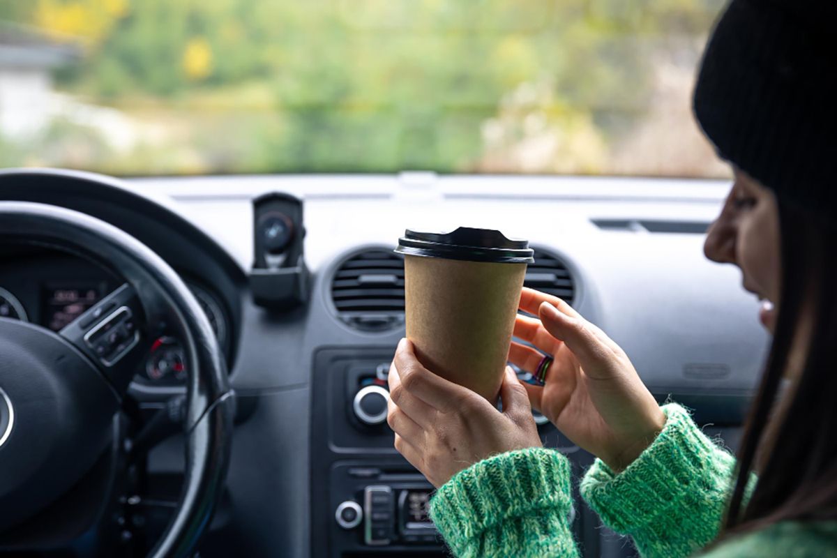 Ilustrasi seorang perempuan yang sedang akan memberikan kopi kepada pengendara mobil.