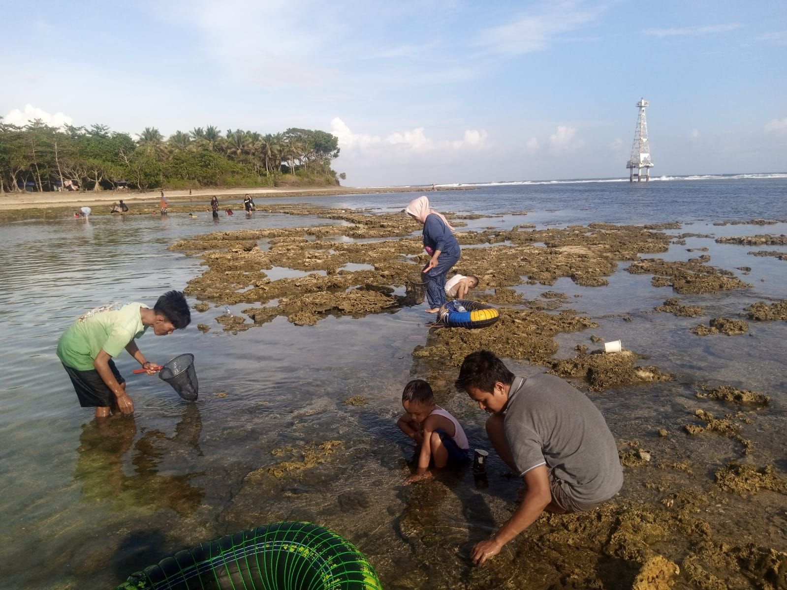 Pengunjung sedang mencari ikan kecil di sela batu karang Pantai Sindangkerta