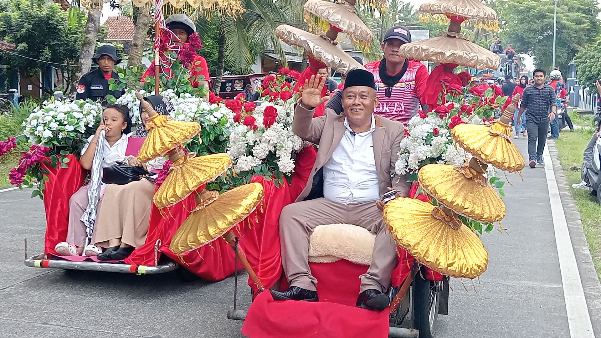 Bak pengantin, Dadang Okta bersama istri dan anaknya melambaikan tangan sambil naik becak motor diantar oleh ribuan warga ke kantor DPC PDI Perjuangan Kab Pangandaran, Jumat, 19 April 2024.
