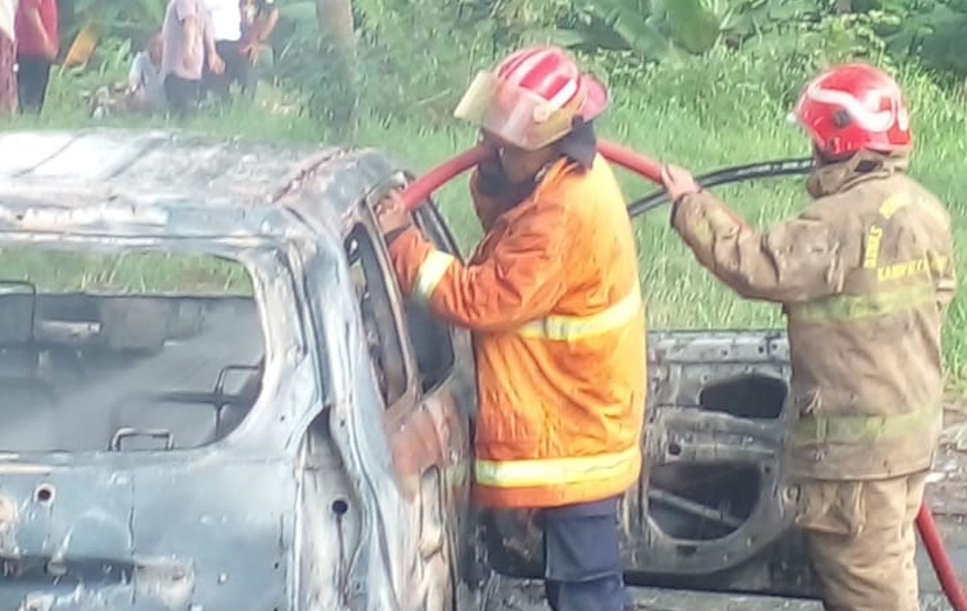 Petugas Damkar berusaha memadamkan satu unit mobile Xenia yang terbakar.