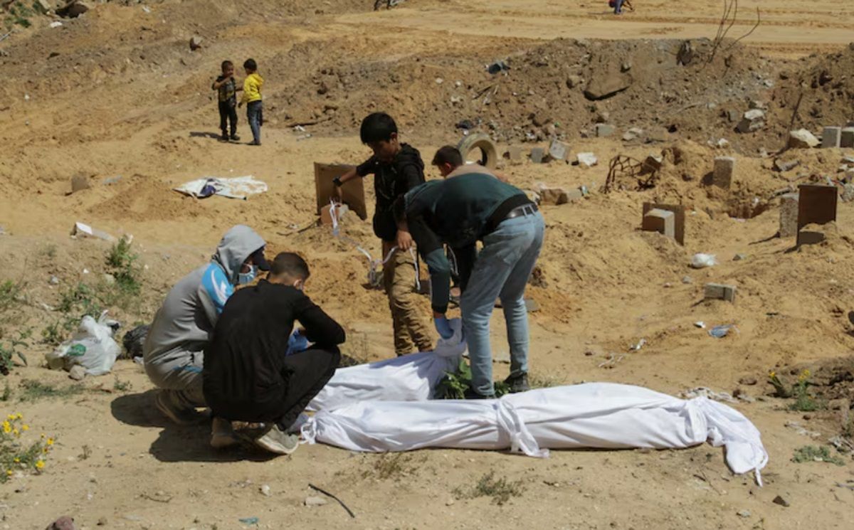 Warga Palestina menutupi jenazah, yang dimakamkan di kuburan massal, di utara Jalur Gaza, 15 April 2024.