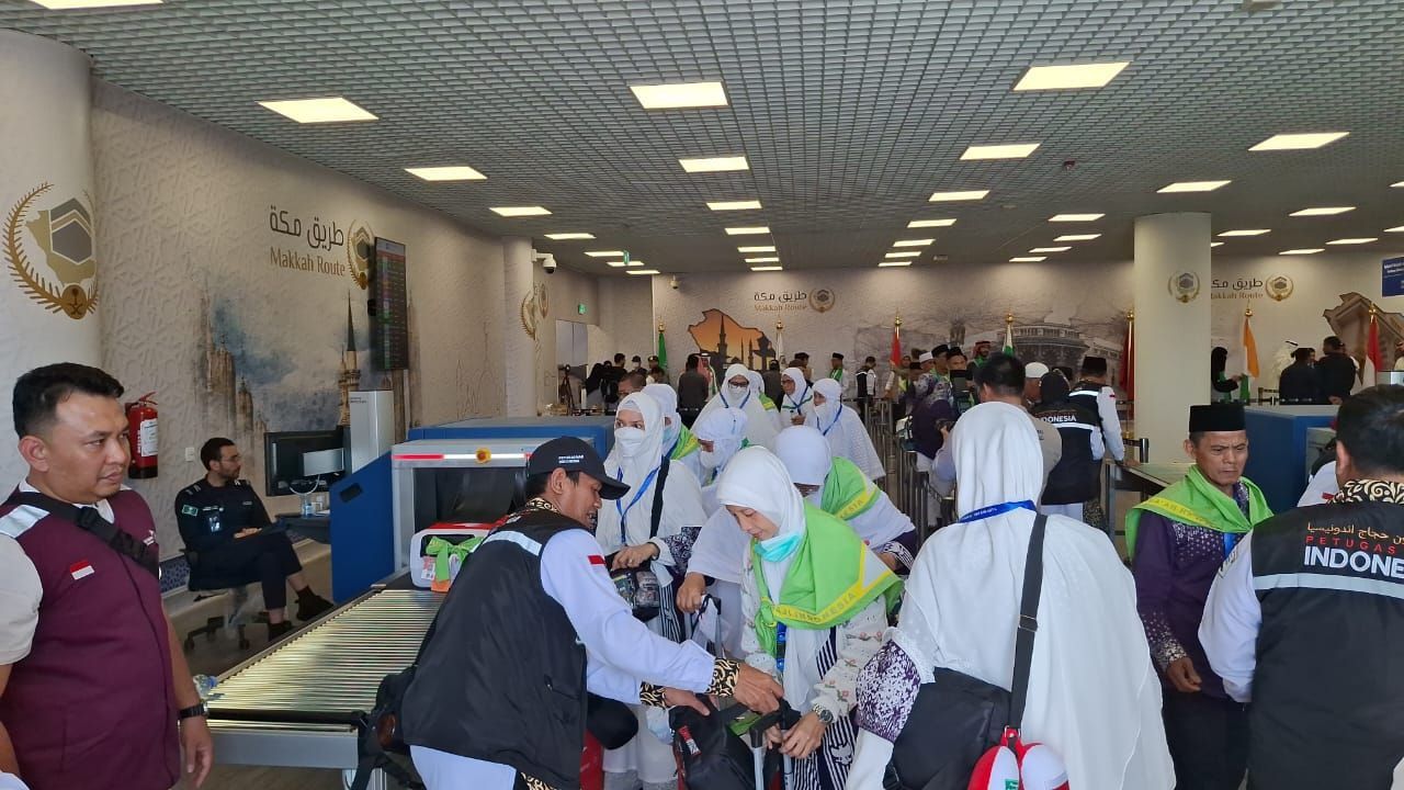 Petugas PPIH Arab Saudi tengah membantu jemaah haji Indonesia menurunkan koper bagasi jemaah di Bandara AMMA Madinah, Ahad, 12 Mei 2024.