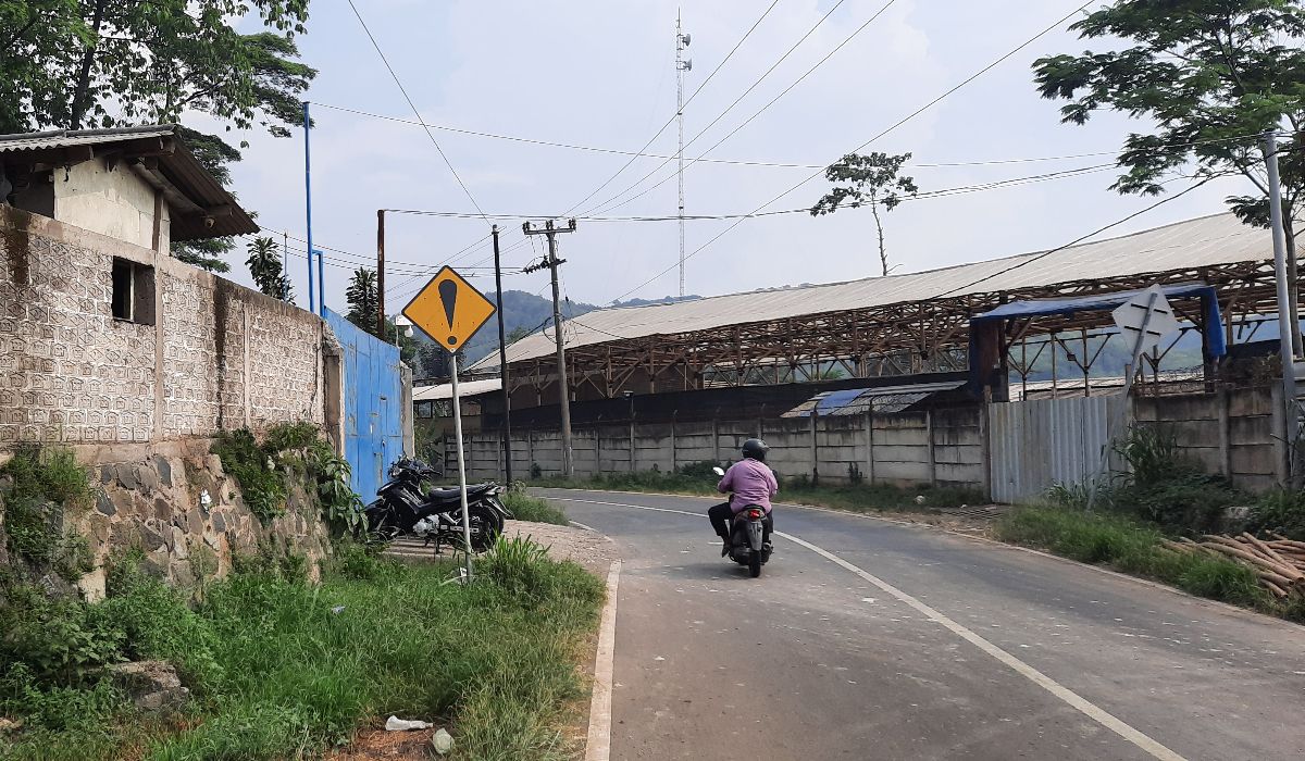 Pengendara melintasi bangunan pabrik pakan di wilayah Kampung Cigangsa, Desa Nanggeleng, Kecamatan Cipeundeuy, Kabupaten Bandung Barat, Senin, 13 Mei 2024. Diduga akibat asap pembuangan pabrik tersebut, sejumlah warga Cigangsa terserang batuk dan sesap napas.