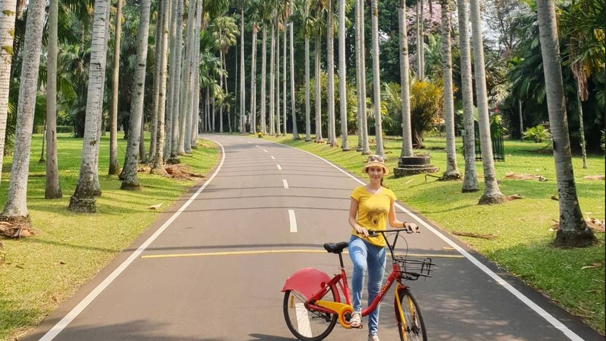 Pengunjung sedang berfoto dengan sepeda di Kebun Raya Bogor