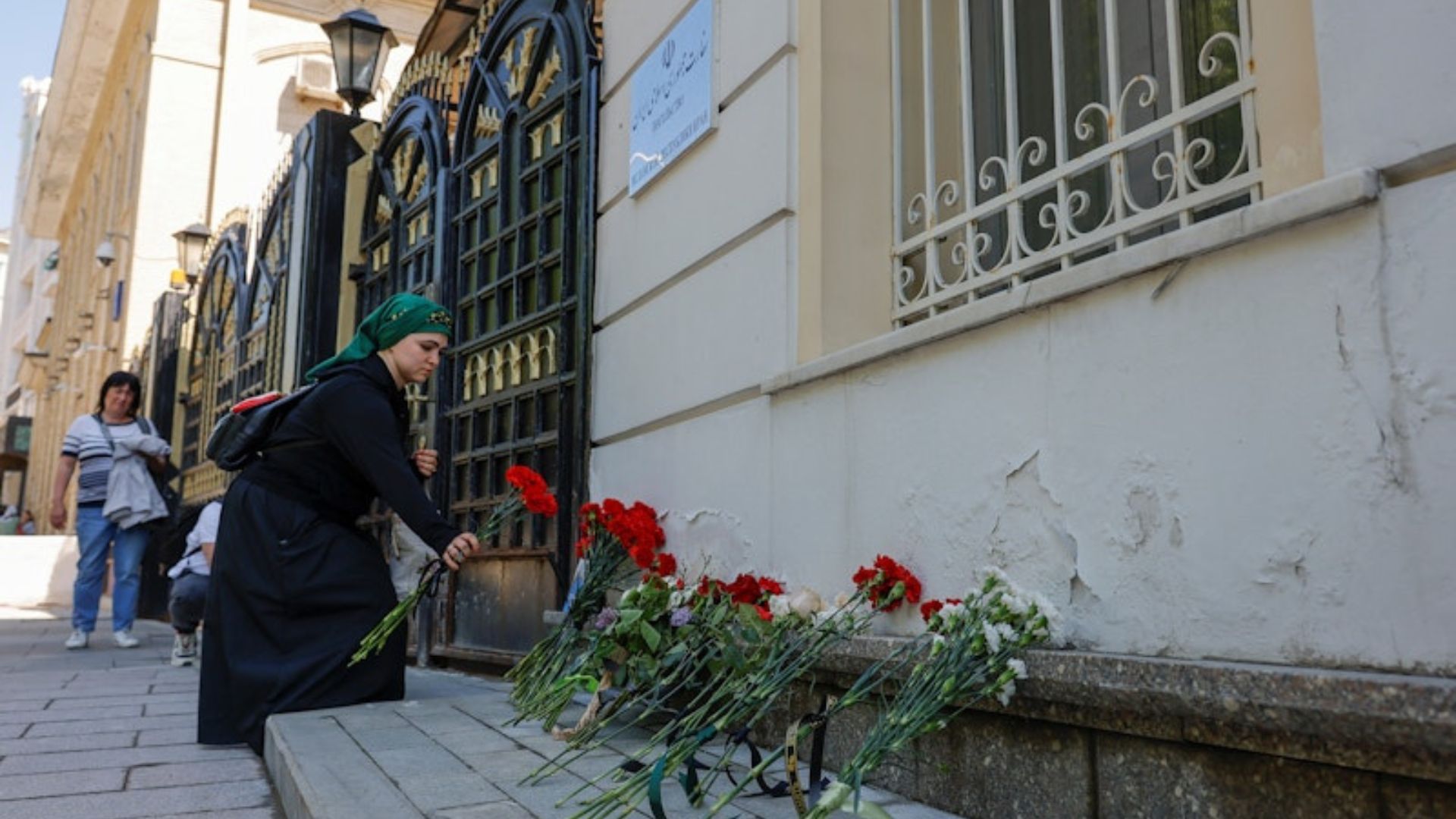 Seorang wanita berbelasungkawa dengan menaruh bunga di depan pintu kedutaan besar Iran di Moskow, Rusia, 20 Mei 2024./ Reuters/Maxim Shemetov