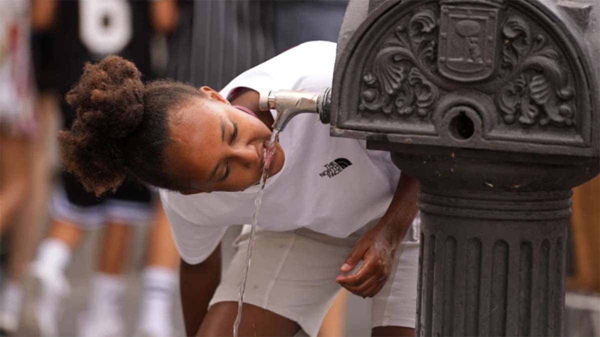 Seorang anak perempuan meminum air dari keran air mancur umum di Madrid, Spanyol, 18 Juli 2023.