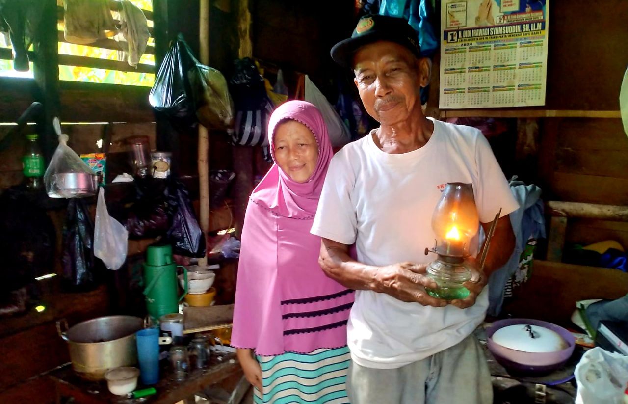 pasangan suami istri, Engkus Kusnadi (69) dan Dede Herlina (45) menyalakan damar saat tiba malam. Karena, tidak ada aliran listrik ke gubuknya selama ini.