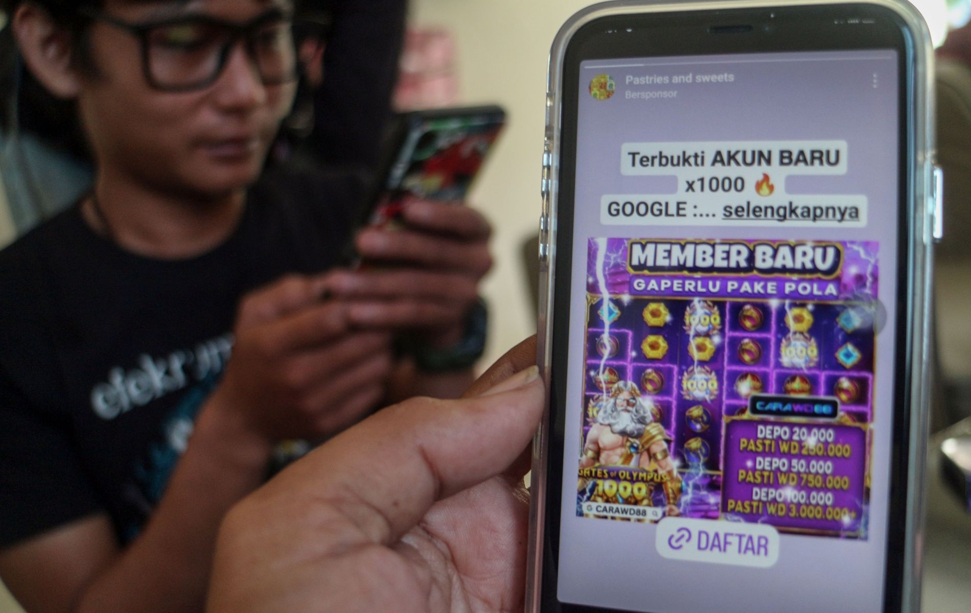 Warga melihat iklan judi online melalui gawainya di Bogor, Jawa Barat, Rabu (26/6/2024).